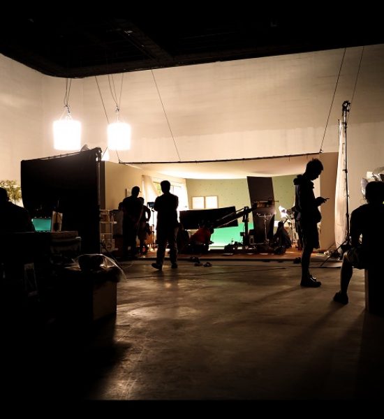 Behind the shooting video production and lighting set for filming which movie crew team working and silhouette shadow of camera and professional equipment in big studio for commercial advertising.